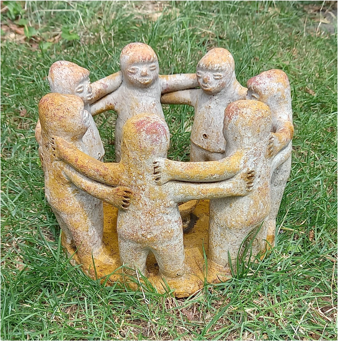 Een beeldje van zeven mensen in een cirkel met een verbindend gebaar van de armen op elkaars schouder